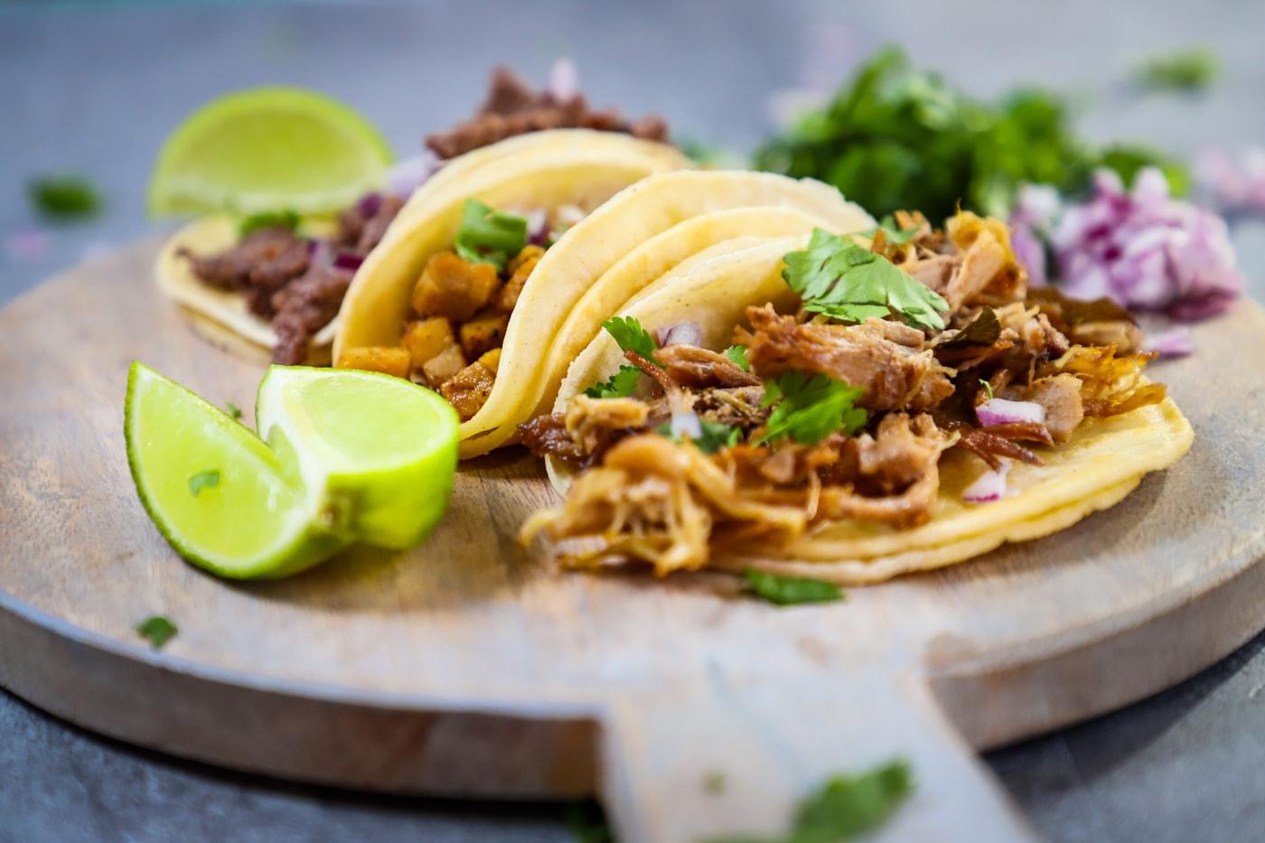 Fresh tacos with lime on a wooden plate