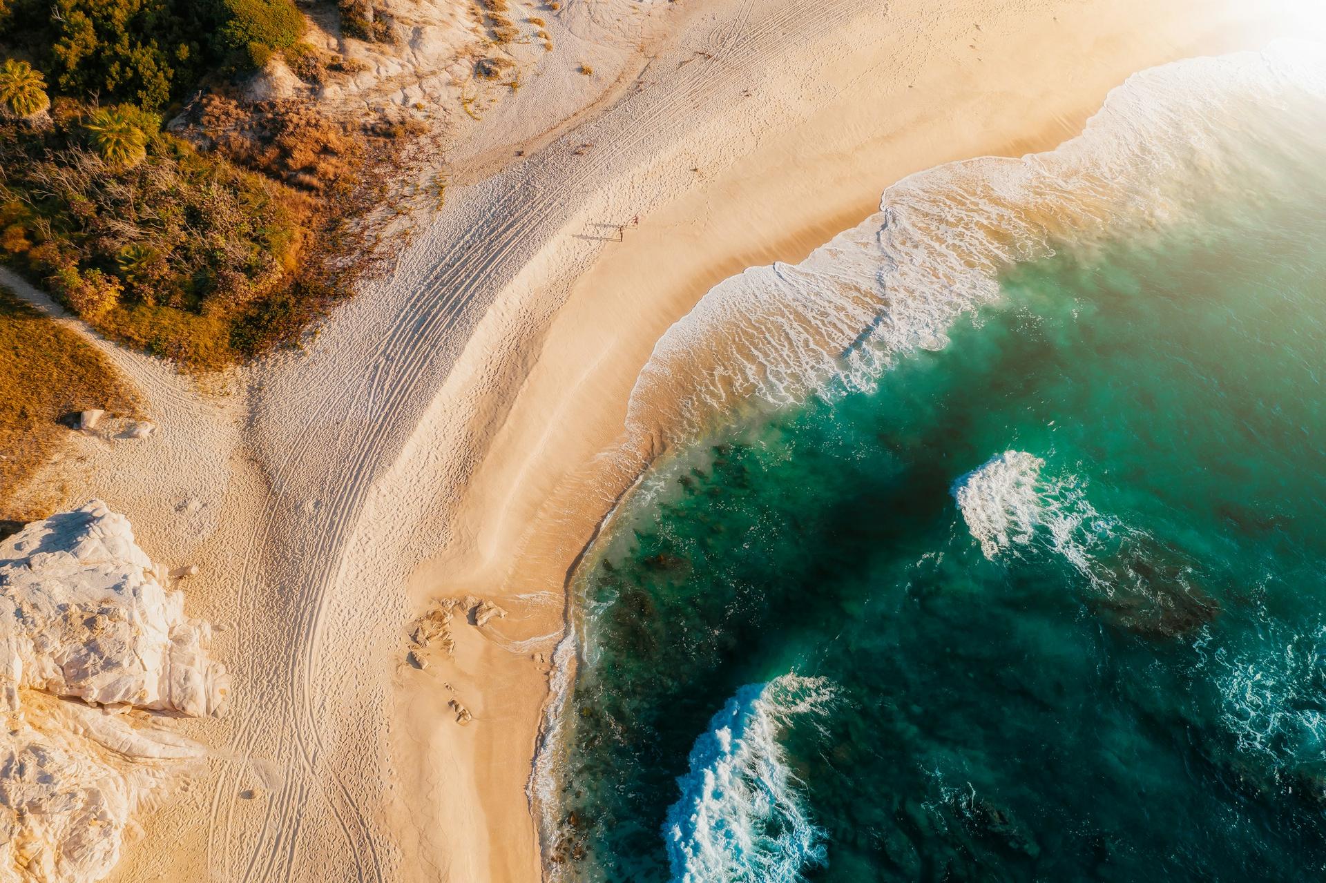 Aerial drone view of a white-sand Los Cabos beach meeting turquoise water