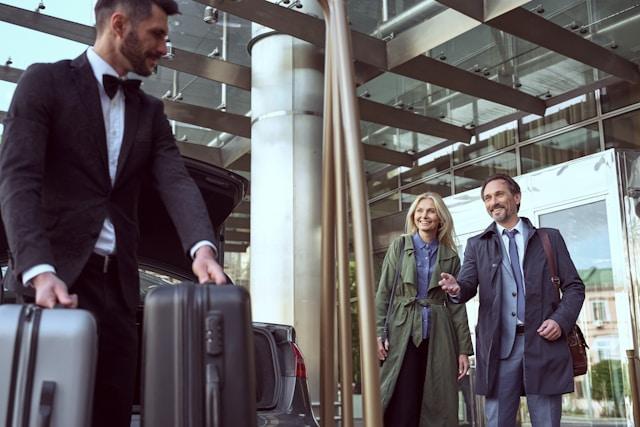 A driver greeting travellers with their luggage